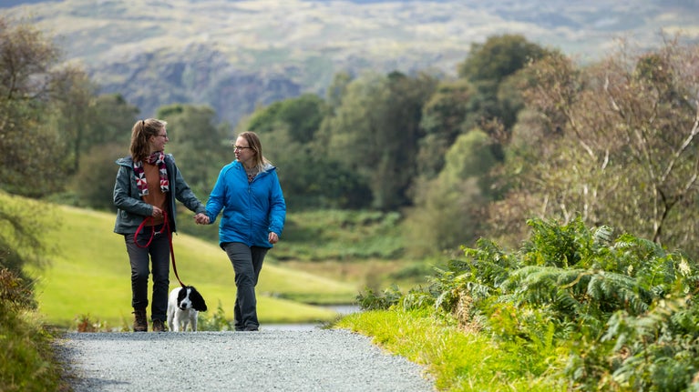 Two female visitors walking at Tarn Hows, Cumbria